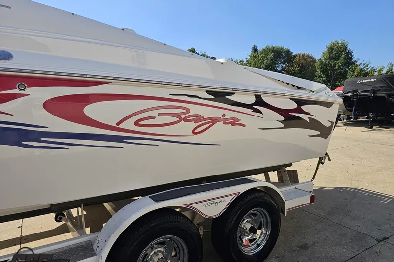 Slide: The Image of 2005 Baja 23 Outlaw boat with vibrant graphics on a trailer, parked outdoors. - 27