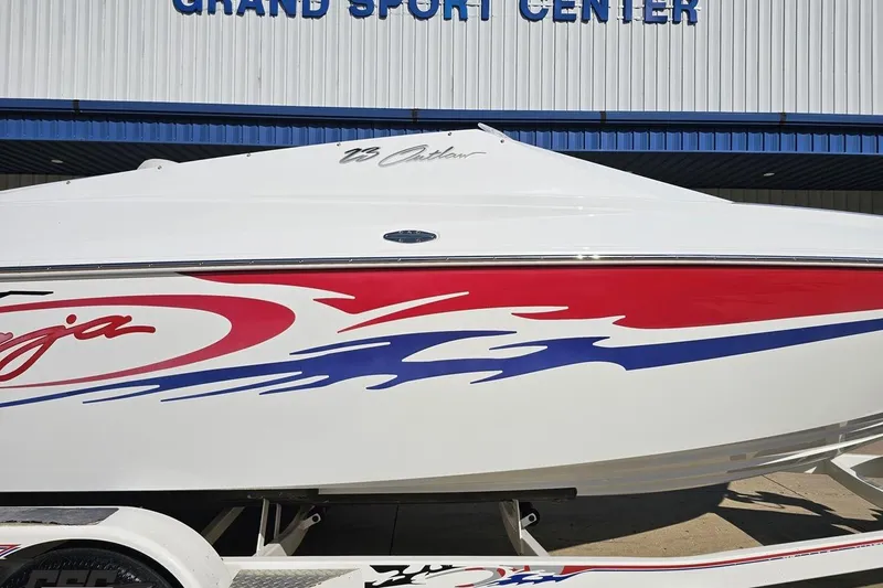 Slide: The Image of 2005 Baja 23 Outlaw boat with vibrant red and blue graphics at Grand Sport Center. - 3