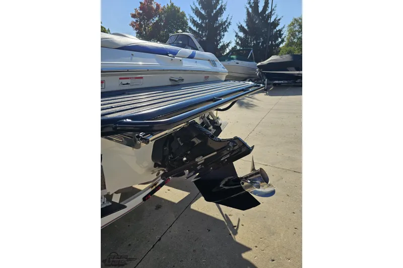 Slide: The Image of 2005 Baja 23 Outlaw boat stern with propeller, parked on concrete, surrounded by trees. - 31