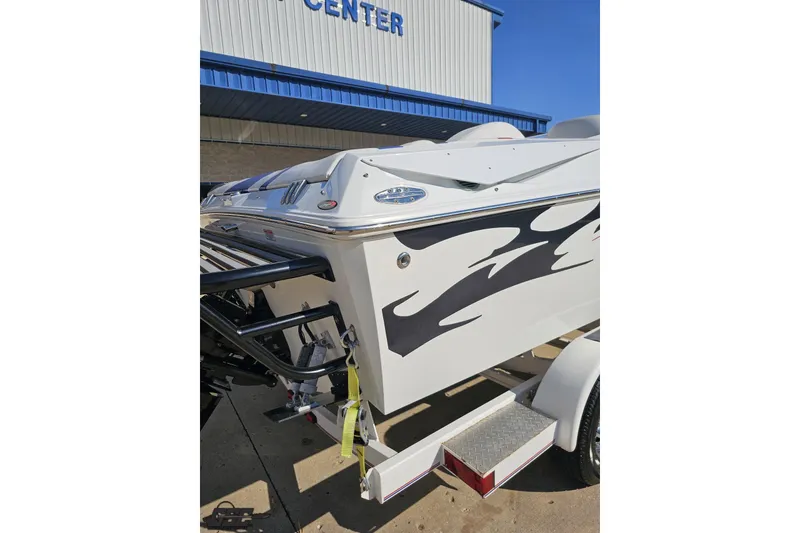 Slide: The Image of 2005 Baja 23 Outlaw boat with flame graphics, parked on a trailer outside a building. - 36