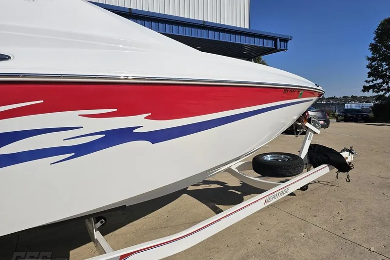 Slide: The Image of 2005 Baja 23 Outlaw boat with red and blue graphics on a trailer. - 5