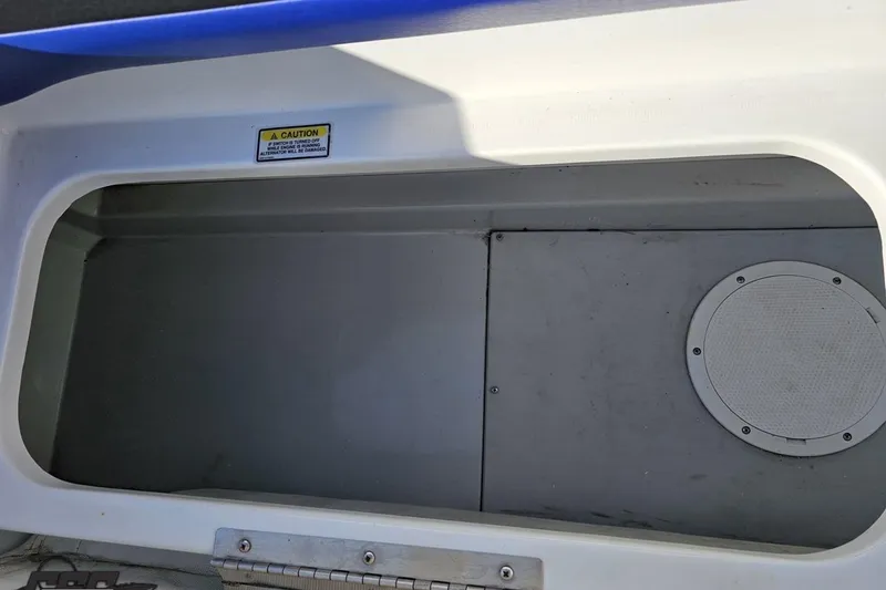Slide: The Image of Storage compartment of a 2005 Baja 23 Outlaw boat, featuring a caution label. - 75