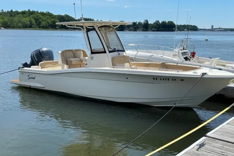 The Image of 2021 Scout 235 XSF boat docked on a calm lake under clear skies. - 1