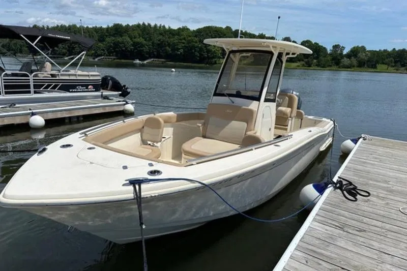 Slide: The Image of 2021 Scout 235 XSF boat docked on a calm lake with trees in the background. - 6
