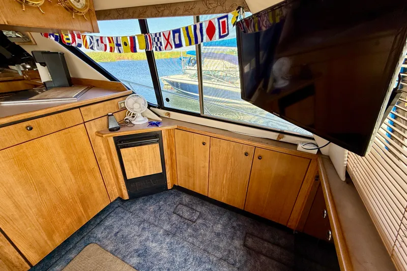 Slide: The Image of 1998 Bayliner 3988 Command Bridge Motoryacht interior with wood cabinets, TV, and nautical flags. - 19
