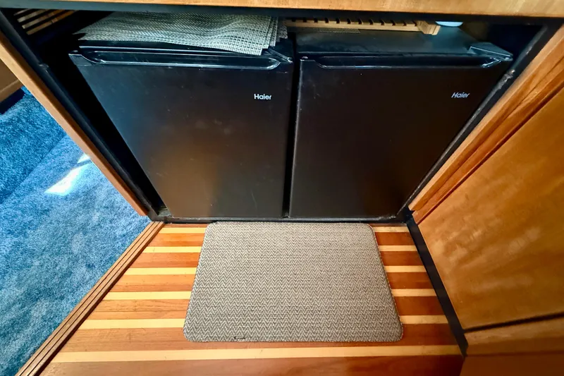 Slide: The Image of 1998 Bayliner 3988 Command Bridge Motoryacht kitchen with stove, nautical-themed towels, and wooden cabinetry. - 25