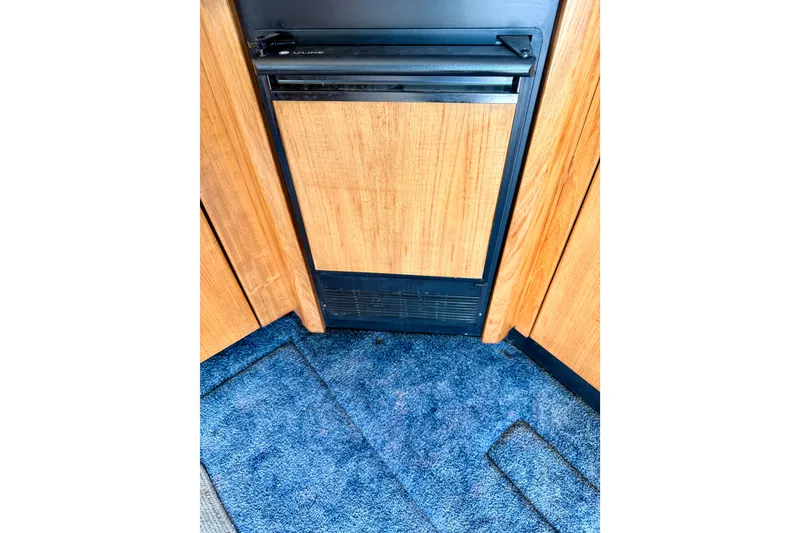 Slide: The Image of 1998 Bayliner 3988 Command Bridge Motoryacht interior with open fridge, wooden flooring. - 28