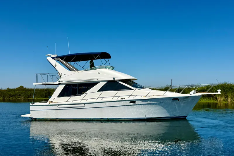 Slide: The Image of 1998 Bayliner 3988 Command Bridge Motoryacht cruising on a calm, sunny waterway. - 3