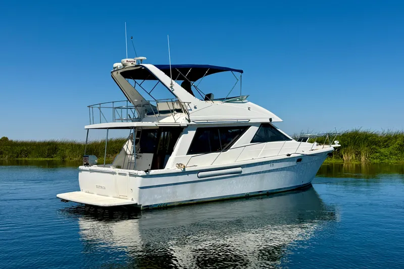 Slide: The Image of 1998 Bayliner 3988 Command Bridge Motoryacht on calm water under clear blue sky. - 4
