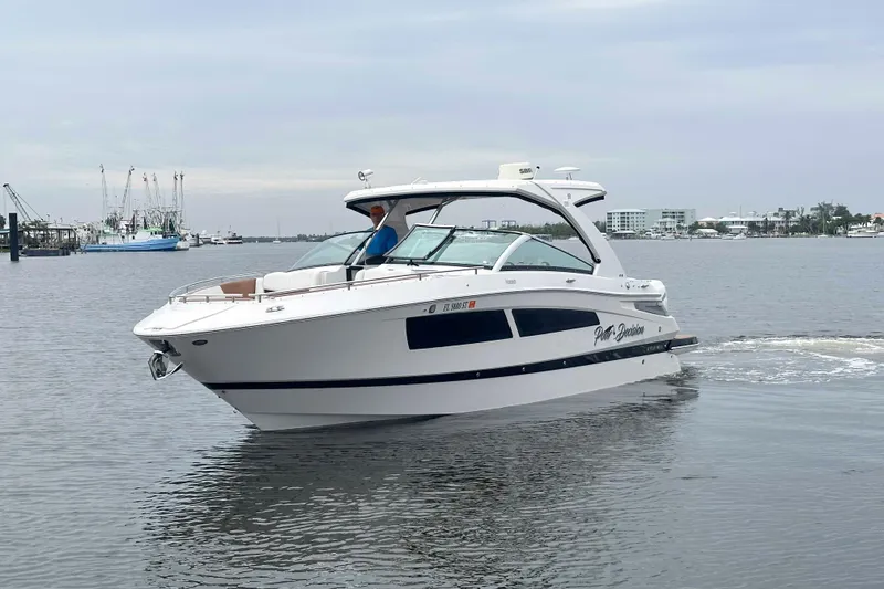 Slide: The Image of 2019 Four Winns H350 OB boat cruising on calm waters near a marina. - 1