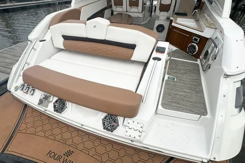Slide: The Image of 2019 Four Winns H350 OB boat interior with tan and white seating, docked at marina. - 12