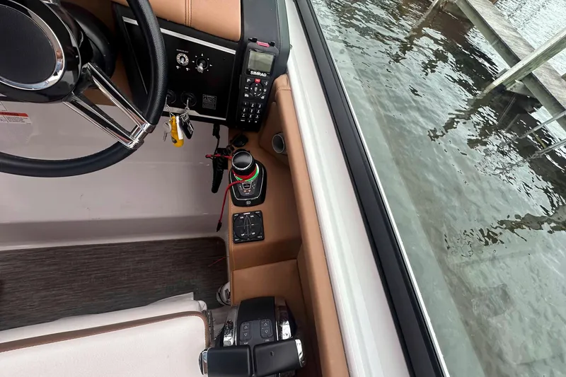 Slide: The Image of 2019 Four Winns H350 OB boat cockpit with steering wheel and control panel by water. - 16