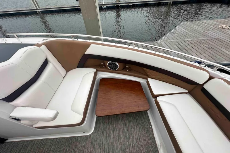 Slide: The Image of 2019 Four Winns H350 OB boat interior with white and brown seating, wooden table, dockside view. - 19