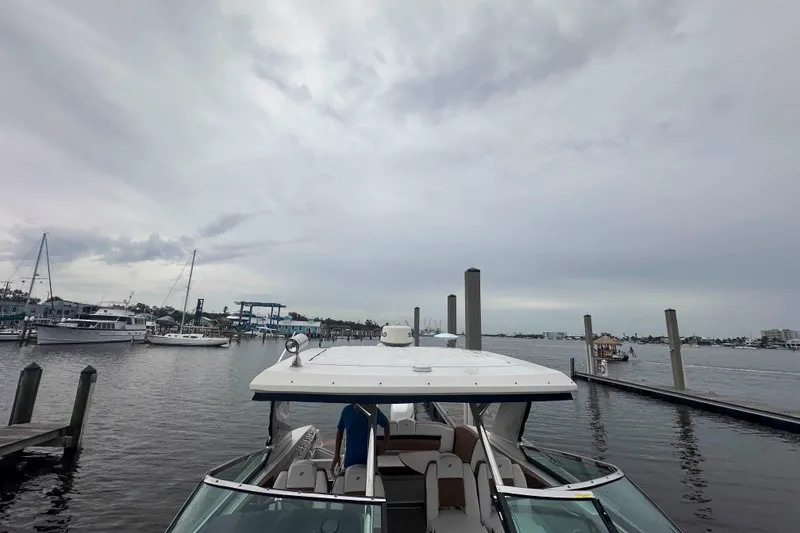 Slide: The Image of 2019 Four Winns H350 OB boat docked in a marina under cloudy skies. - 28