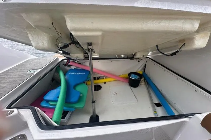 Slide: The Image of Open storage compartment of 2019 Four Winns H350 OB boat with pool noodles and gear. - 36