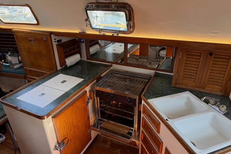 Slide: The Image of Interior of 1977 Cheoy Lee Offshore 41 ketch, featuring a compact kitchen with stove and sink. - 12