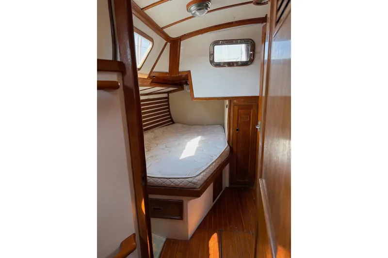 Slide: The Image of 1977 Cheoy Lee Offshore 41 ketch cabin with wooden interior and cozy bed. - 22