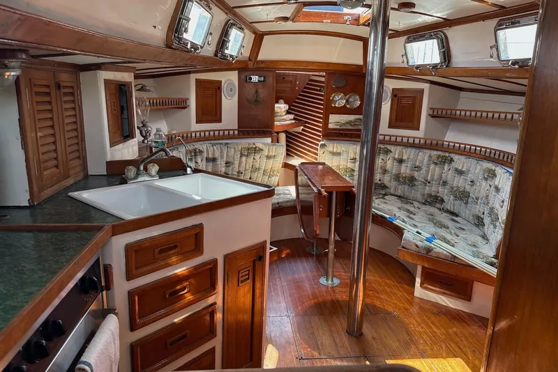 Slide: The Image of Interior of 1977 Cheoy Lee Offshore 41 ketch, featuring wood finishes and cozy seating area. - 8