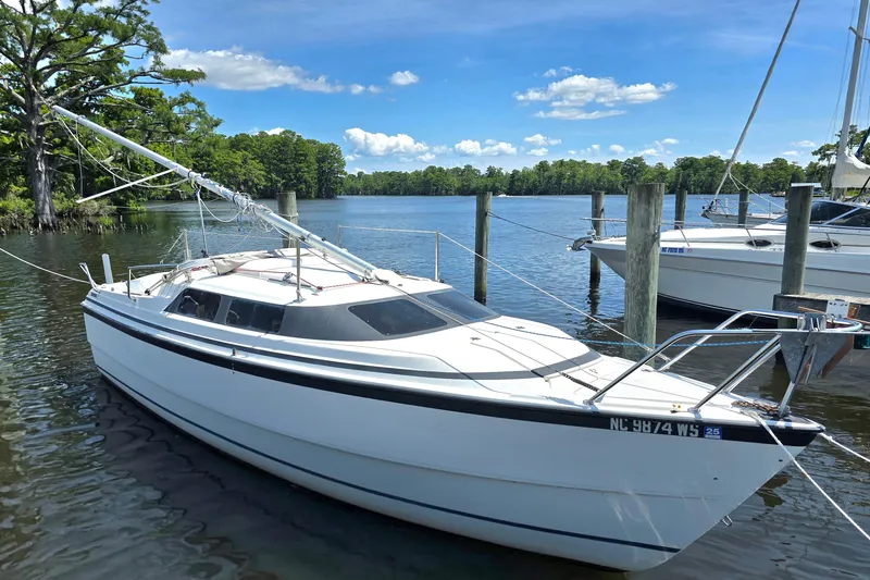 Slide: The Image of 2002 MacGregor 26X Powersailer docked on a serene lake with lush greenery. - 1