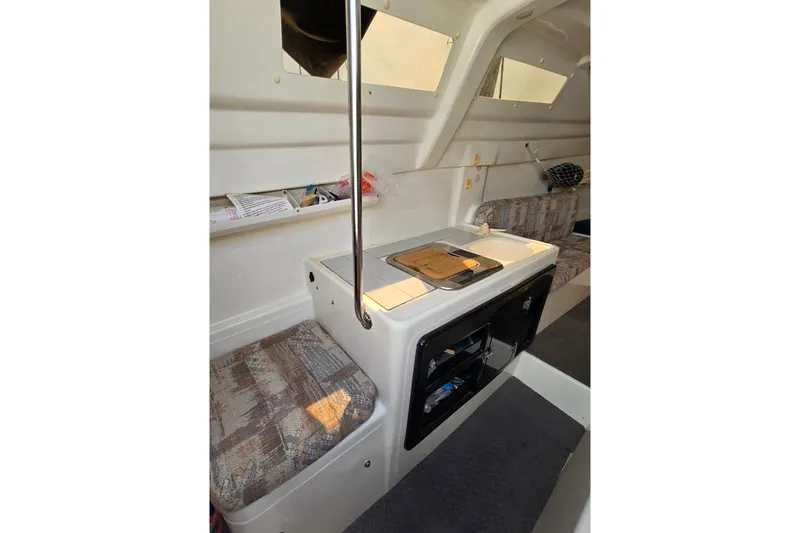 Slide: The Image of Interior of 2002 MacGregor 26X Powersailer with compact kitchen and seating area. - 10