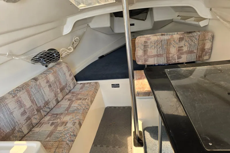 Slide: The Image of 2002 MacGregor 26X Powersailer interior with seating and table, showcasing compact cabin design. - 11