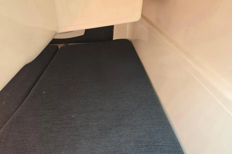 Slide: The Image of Interior cabin view of a 2002 MacGregor 26X Powersailer with dark blue cushions. - 15