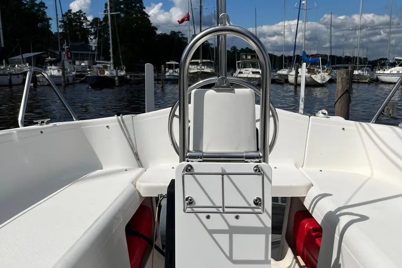 Slide: The Image of 2002 MacGregor 26X Powersailer cockpit view at marina, surrounded by boats and trees. - 17