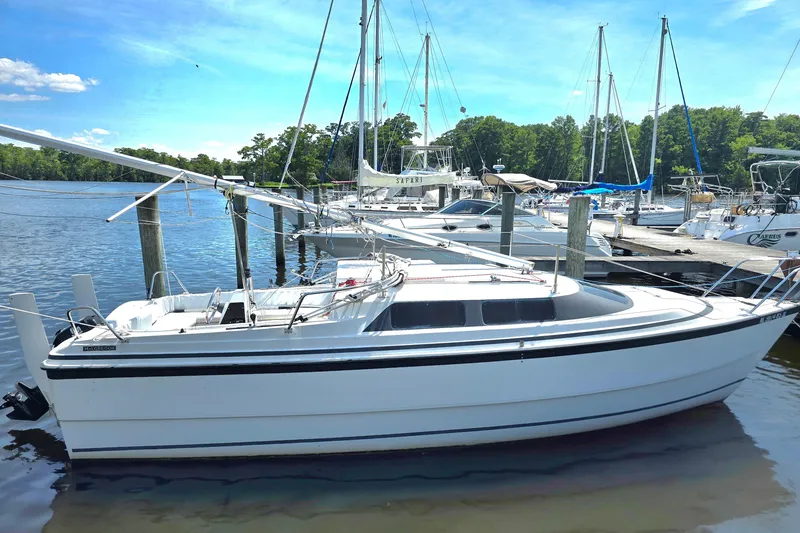 Slide: The Image of 2002 MacGregor 26X Powersailer docked at a marina, surrounded by other boats. - 2