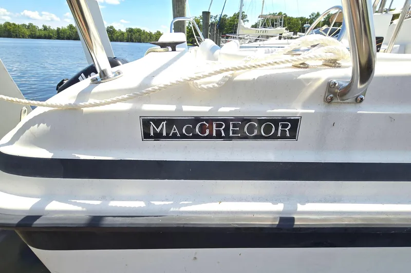 Slide: The Image of 2002 MacGregor 26X Powersailer docked, featuring brand logo and stainless steel railings. - 5