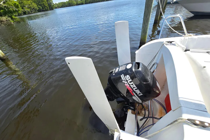 Slide: The Image of 2002 MacGregor 26X Powersailer with Suzuki outboard motor on calm water. - 6