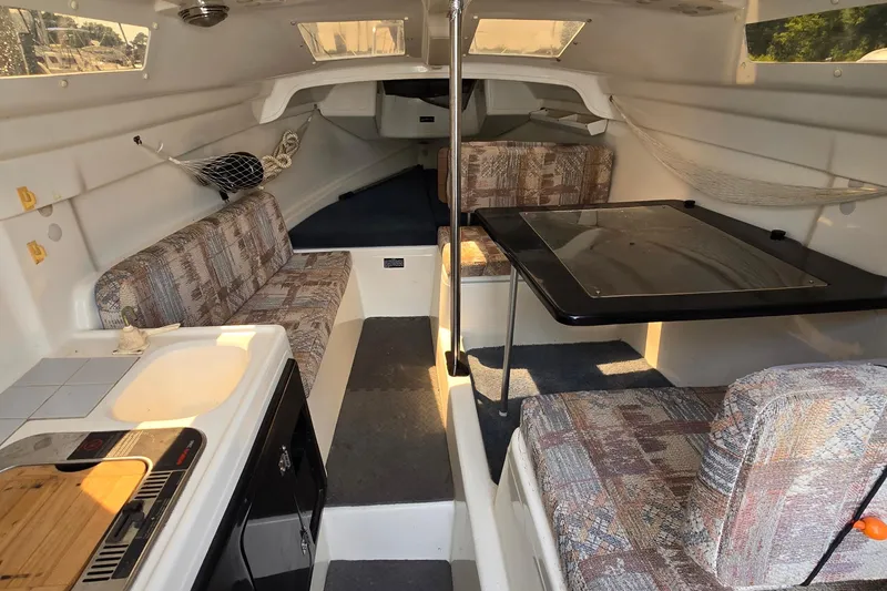 Slide: The Image of Interior of a 2002 MacGregor 26X Powersailer with seating, table, and kitchenette. - 9