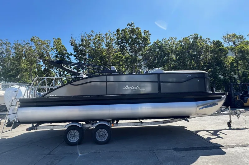 Slide: The Image of 2026 Barletta ARIA 22UC pontoon boat on trailer, parked outdoors. - 13