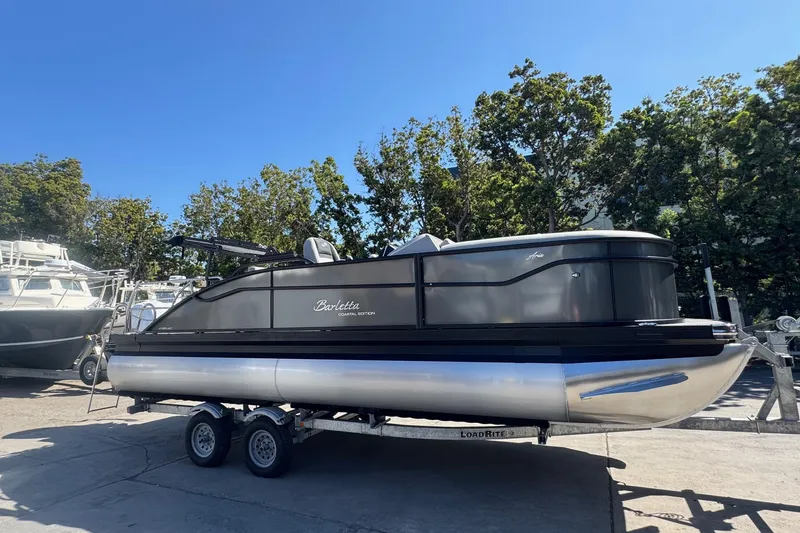 Slide: The Image of 2026 Barletta ARIA 22UC pontoon boat on trailer, parked outdoors. - 14