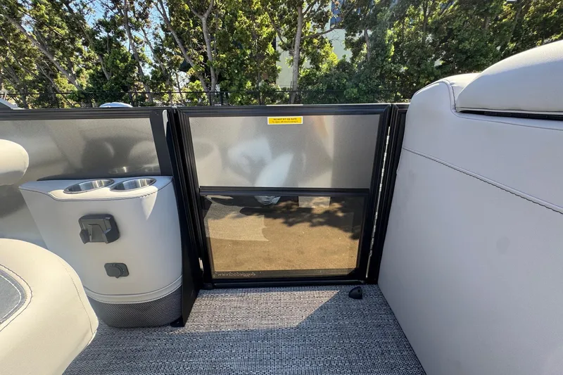 Slide: The Image of 2026 Barletta ARIA 22UC interior with cup holders and seating, surrounded by trees. - 49