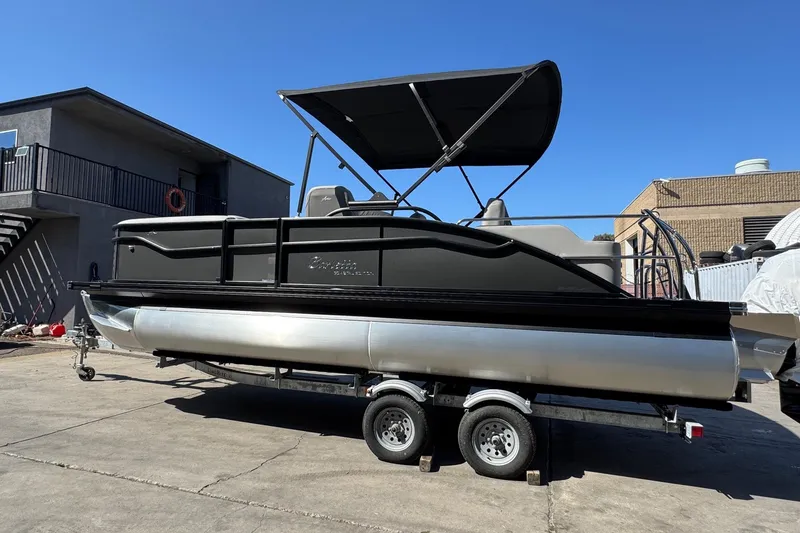 Slide: The Image of 2026 Barletta ARIA 22UC pontoon boat on trailer, parked outdoors under clear blue sky. - 69