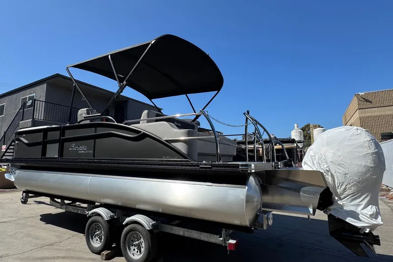 Slide: The Image of 2026 Barletta ARIA 22UC pontoon boat with canopy on trailer, parked outdoors. - 70
