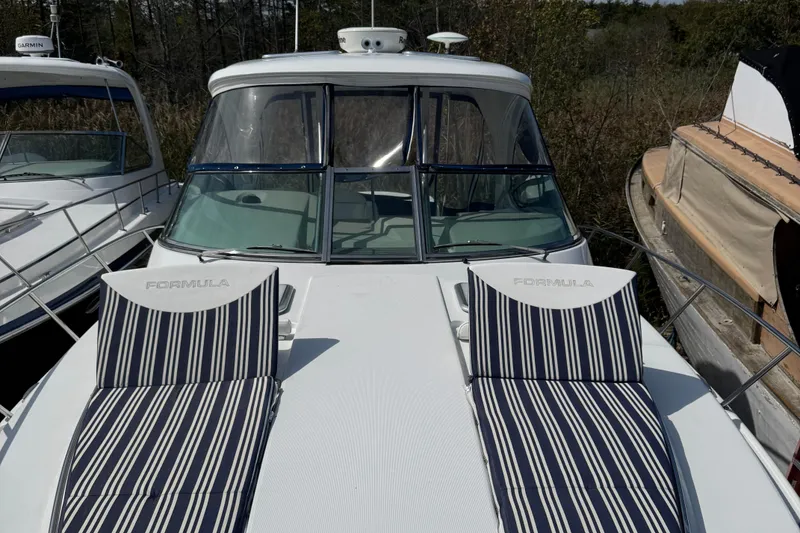 Slide: The Image of 2011 Formula 37 Performance Cruiser with striped deck chairs, docked among other boats. - 10