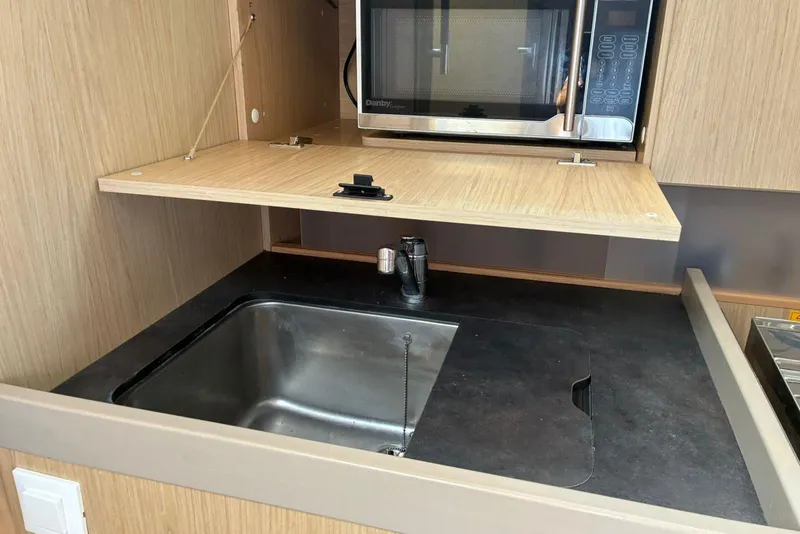 Slide: The Image of Modern kitchen area in a 2020 Beneteau Oceanis 41.1 yacht, featuring a sink and microwave. - 14
