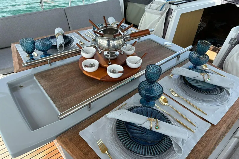 Slide: The Image of Elegant dining setup on 2020 Beneteau Oceanis 41.1 yacht with fondue set and blue glassware. - 8