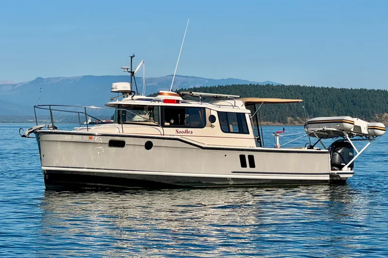 Slide: The Image of 2024 Ranger Tugs R-27 boat on calm water with scenic mountain backdrop. - 24