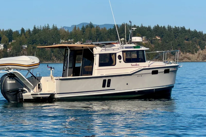 Slide: The Image of 2024 Ranger Tugs R-27 boat on calm water with scenic forested background. - 26