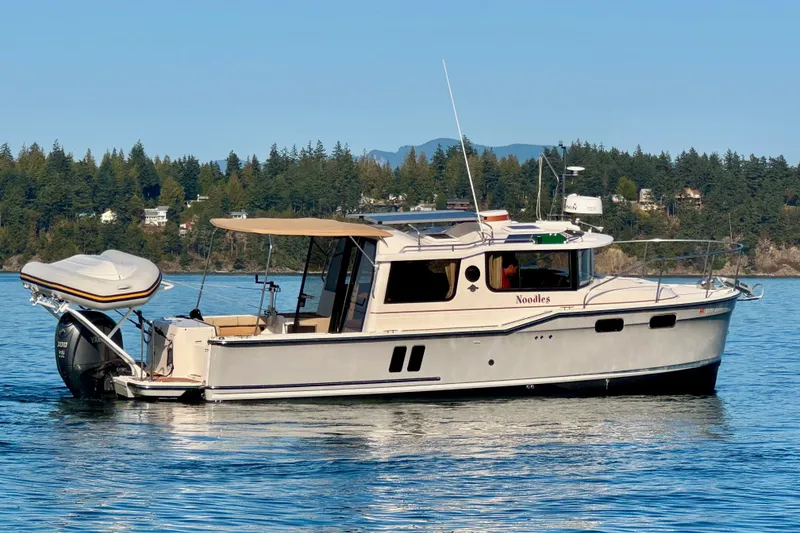 Slide: The Image of 2024 Ranger Tugs R-27 boat on calm water, scenic forested background. - 27