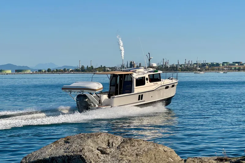 Slide: The Image of 2024 Ranger Tugs R-27 cruising on a sunny day near industrial shoreline. - 37