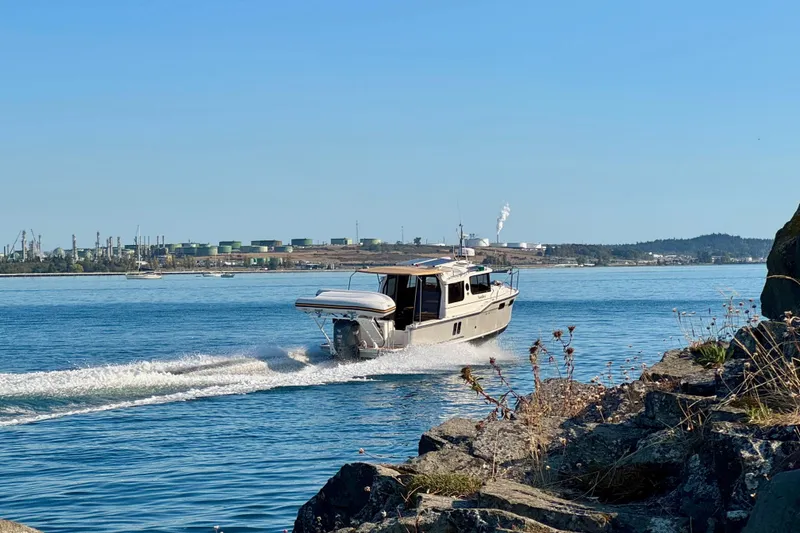 Slide: The Image of 2024 Ranger Tugs R-27 cruising on a sunny day near rocky shoreline. - 38