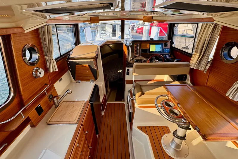 Slide: The Image of 2024 Ranger Tugs R-27 interior with wood finish, kitchenette, and helm station. - 7