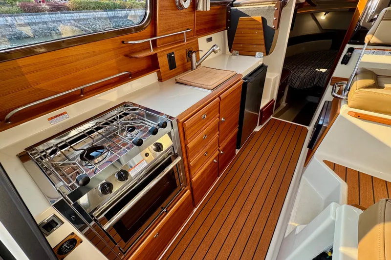 Slide: The Image of 2024 Ranger Tugs R-27 interior with modern kitchen, wood cabinetry, and compact design. - 8