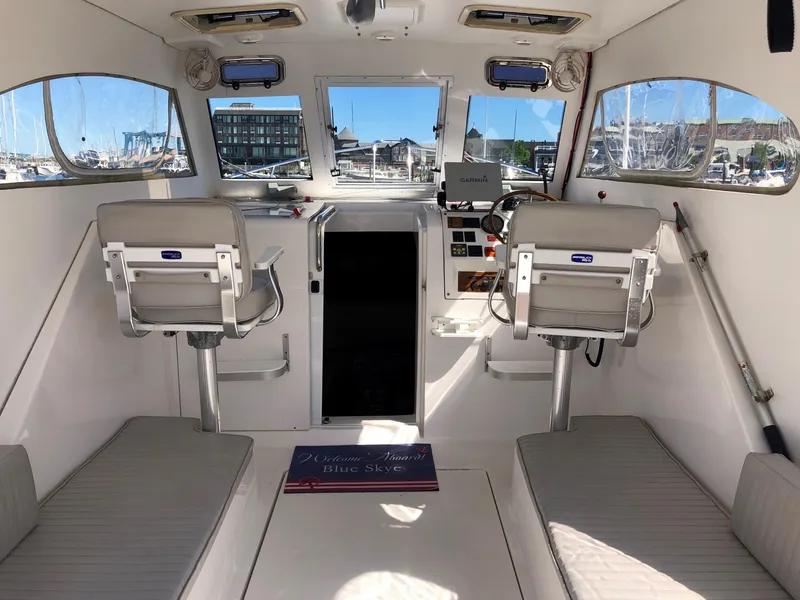 Slide: The Image of 2003 Mainship 30 Pilot II Hardtop interior with helm, seating, and marina view. - 11