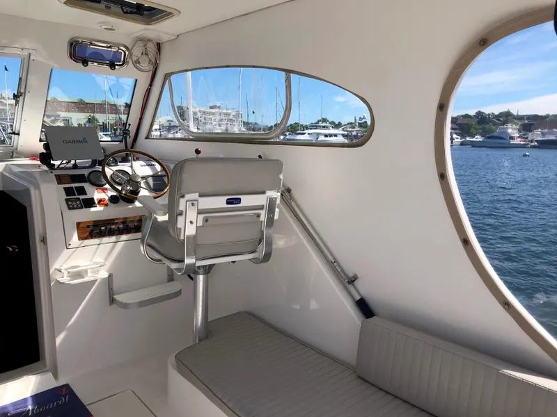 Slide: The Image of 2003 Mainship 30 Pilot II Hardtop interior with helm, seating, and waterfront view. - 13