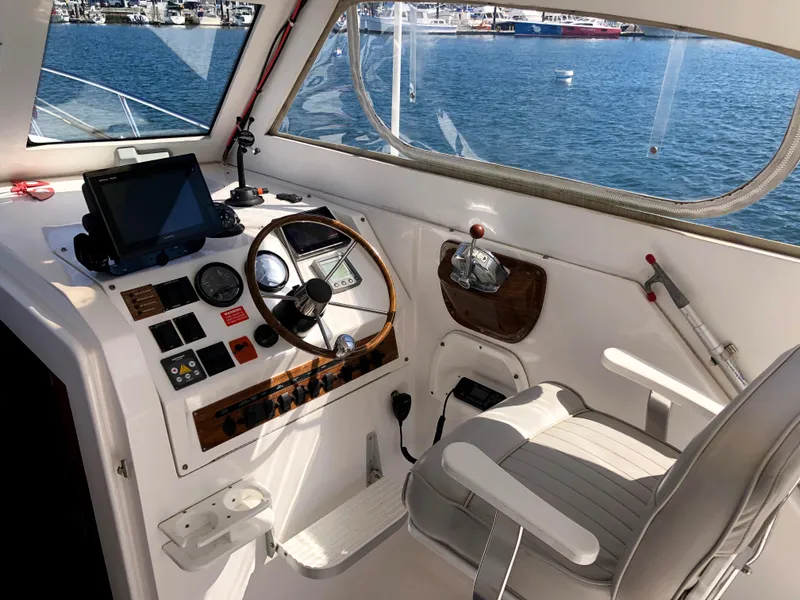 Slide: The Image of 2003 Mainship 30 Pilot II boat cockpit with steering wheel, navigation equipment, and ocean view. - 15