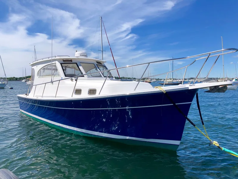 Slide: The Image of 2003 Mainship 30 Pilot II Hardtop boat on water, blue hull, clear sky background. - 2
